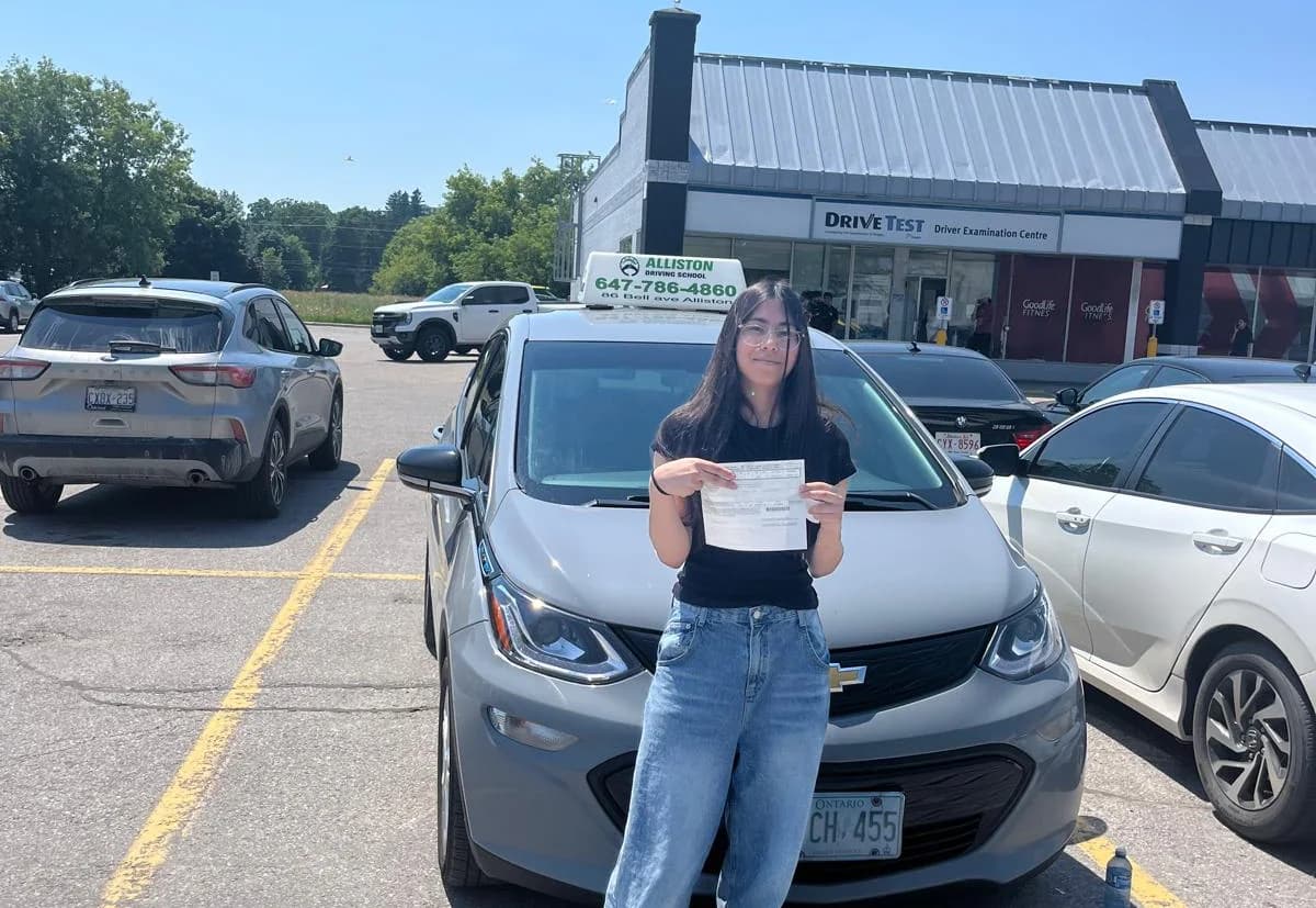An Alliston Driving School student beside the instructor car after road-test preparation.